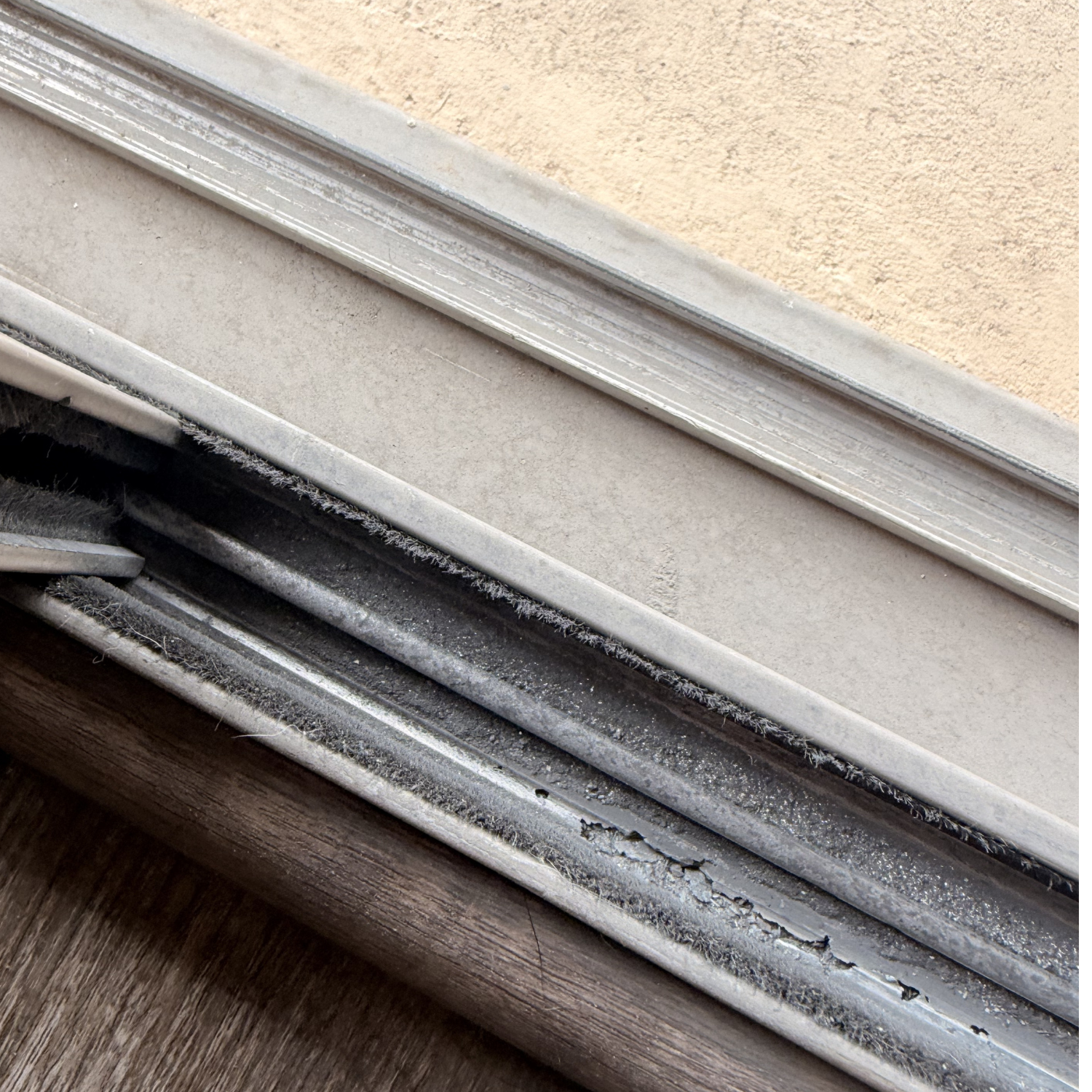 Close-up of a dirty and worn sliding door track with brush seals.