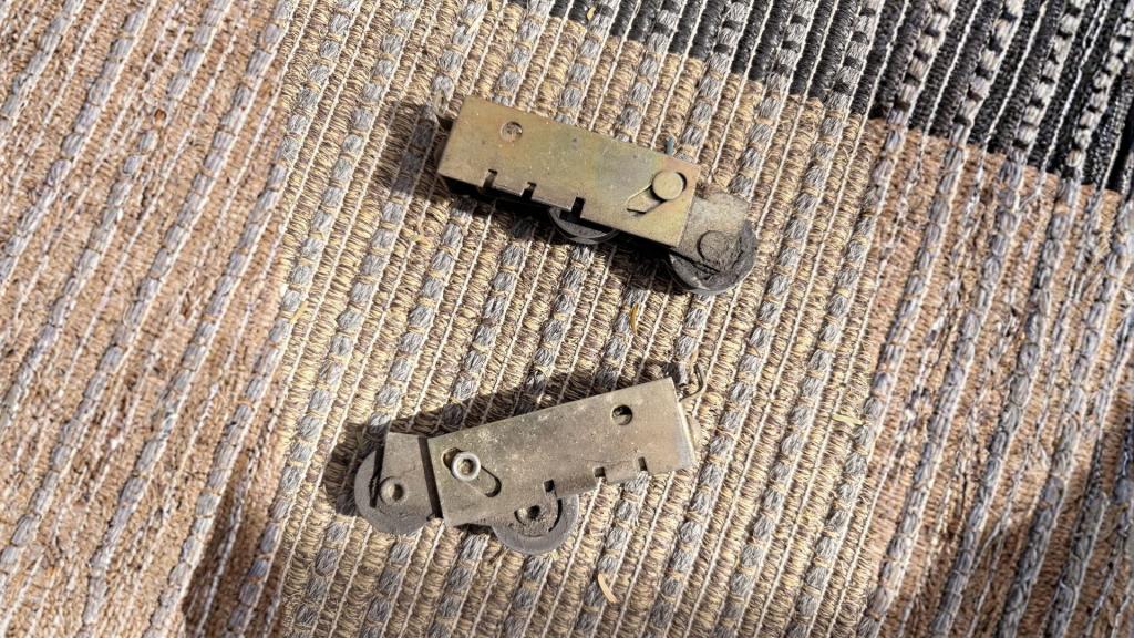 Close-up of worn sliding door rollers removed from the door, showing dirt buildup and damage that require replacement.
