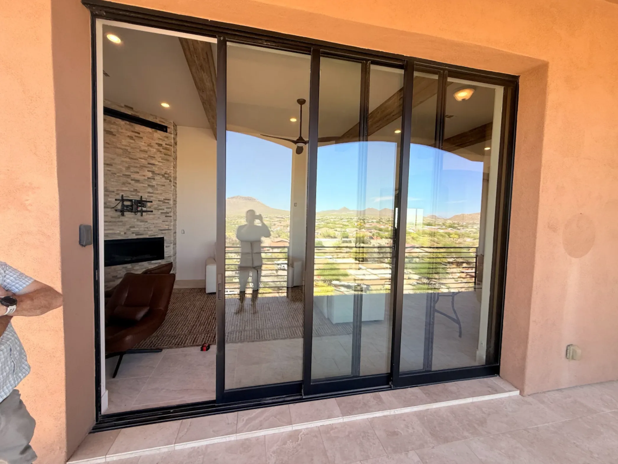 Sliding glass doors reflecting a person and a desert landscape.
