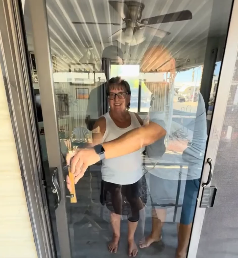 Woman opening a glass sliding door, with a man reflected beside her.