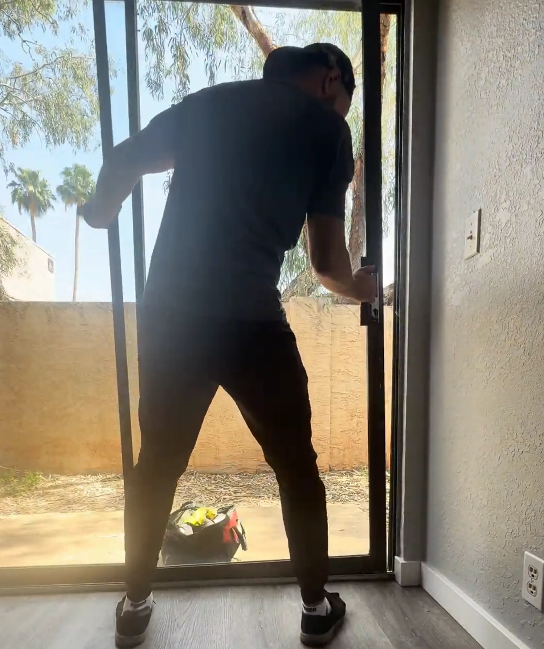 Man installing a sliding glass door with tools on the ground