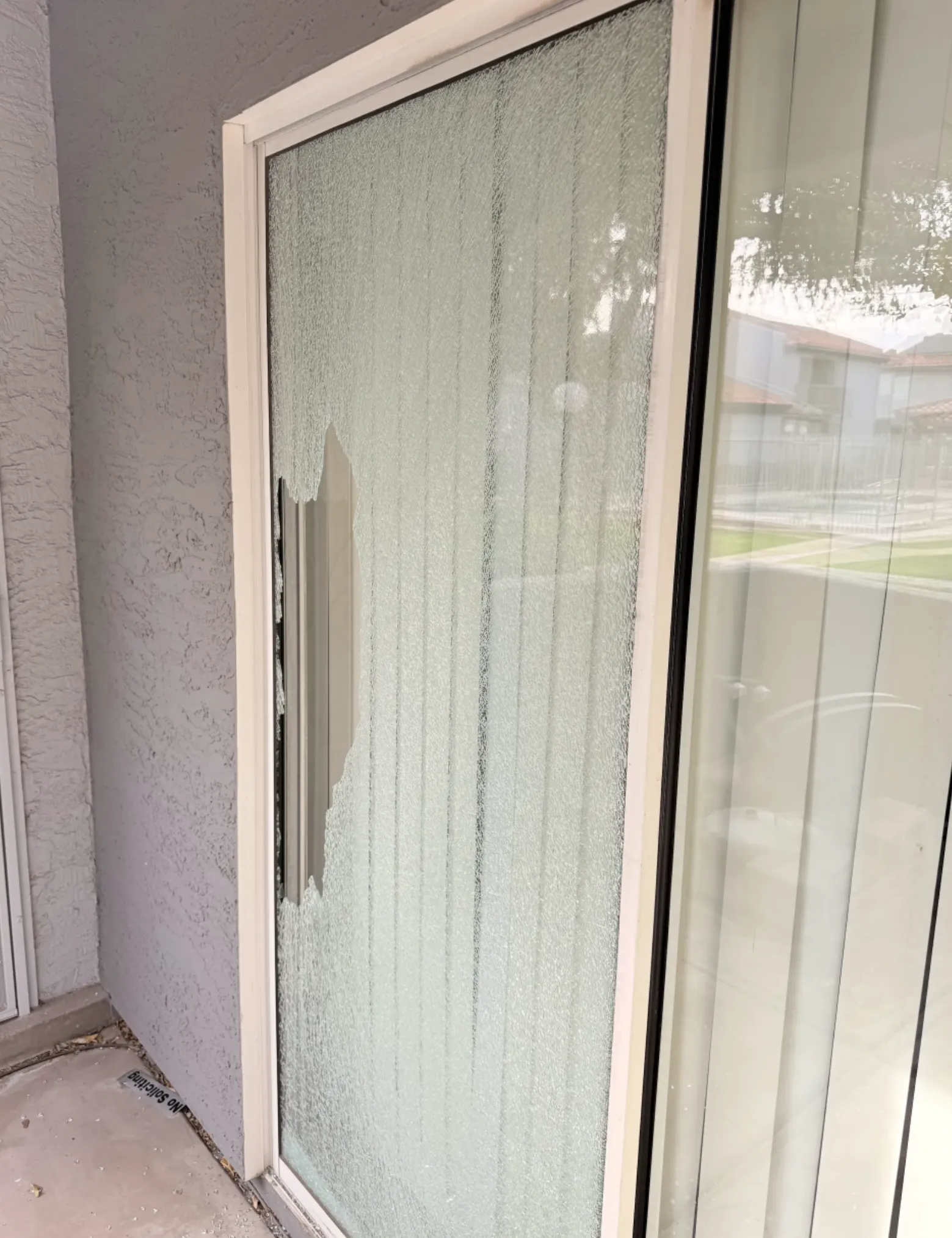 Broken glass sliding door with a large jagged hole near the handle.