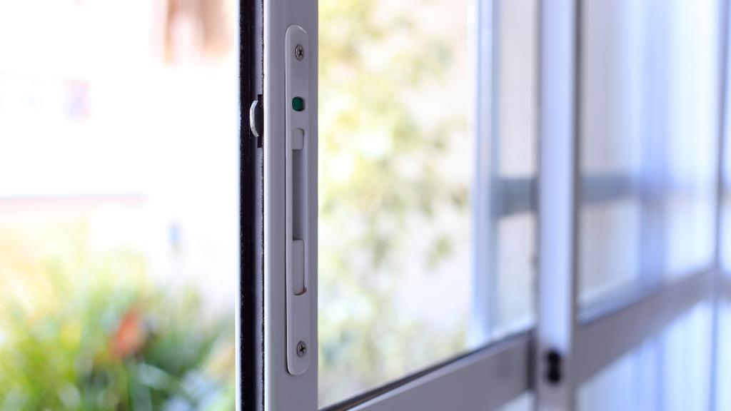 Close-up of a white sliding patio door lock and latch, showing the type of hardware often checked during sliding door lock repair