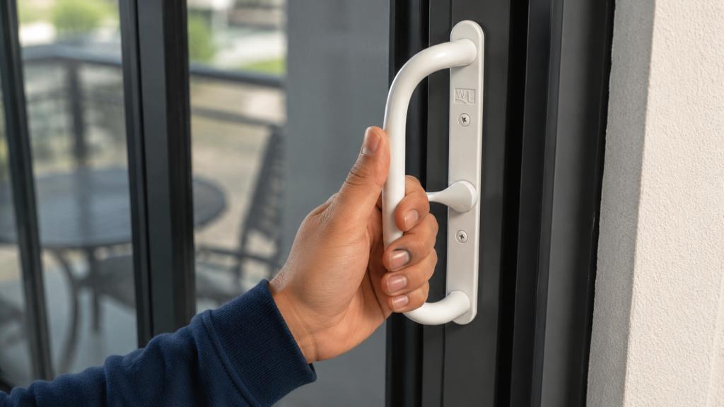 Hand testing a sliding door lock before summer travel for home security and sliding door repair