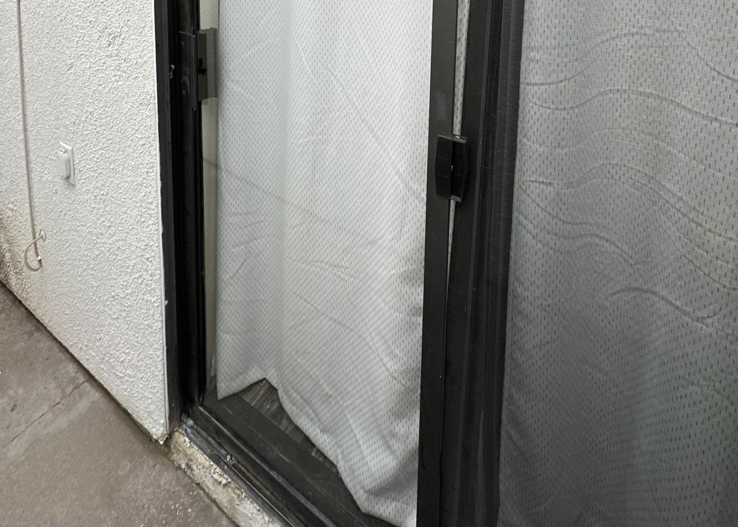 Sliding Glass Door with White Curtains and Screen Close-up of a glass sliding door with white curtains and a screen door.
