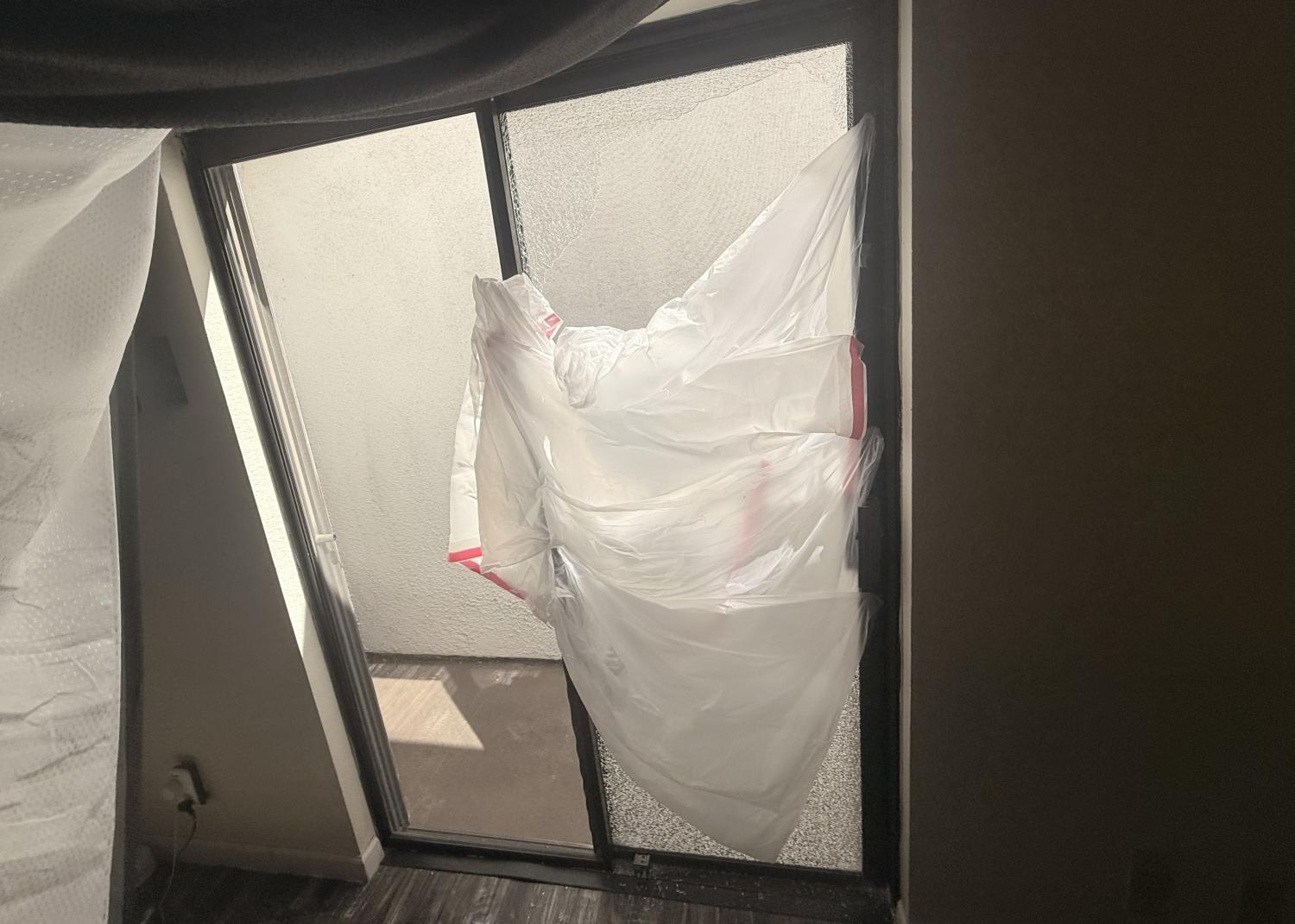 Temporary Repair: Plastic Bags Cover Broken Glass Door Plastic bags taped over a broken glass door, with sunlight shining through.